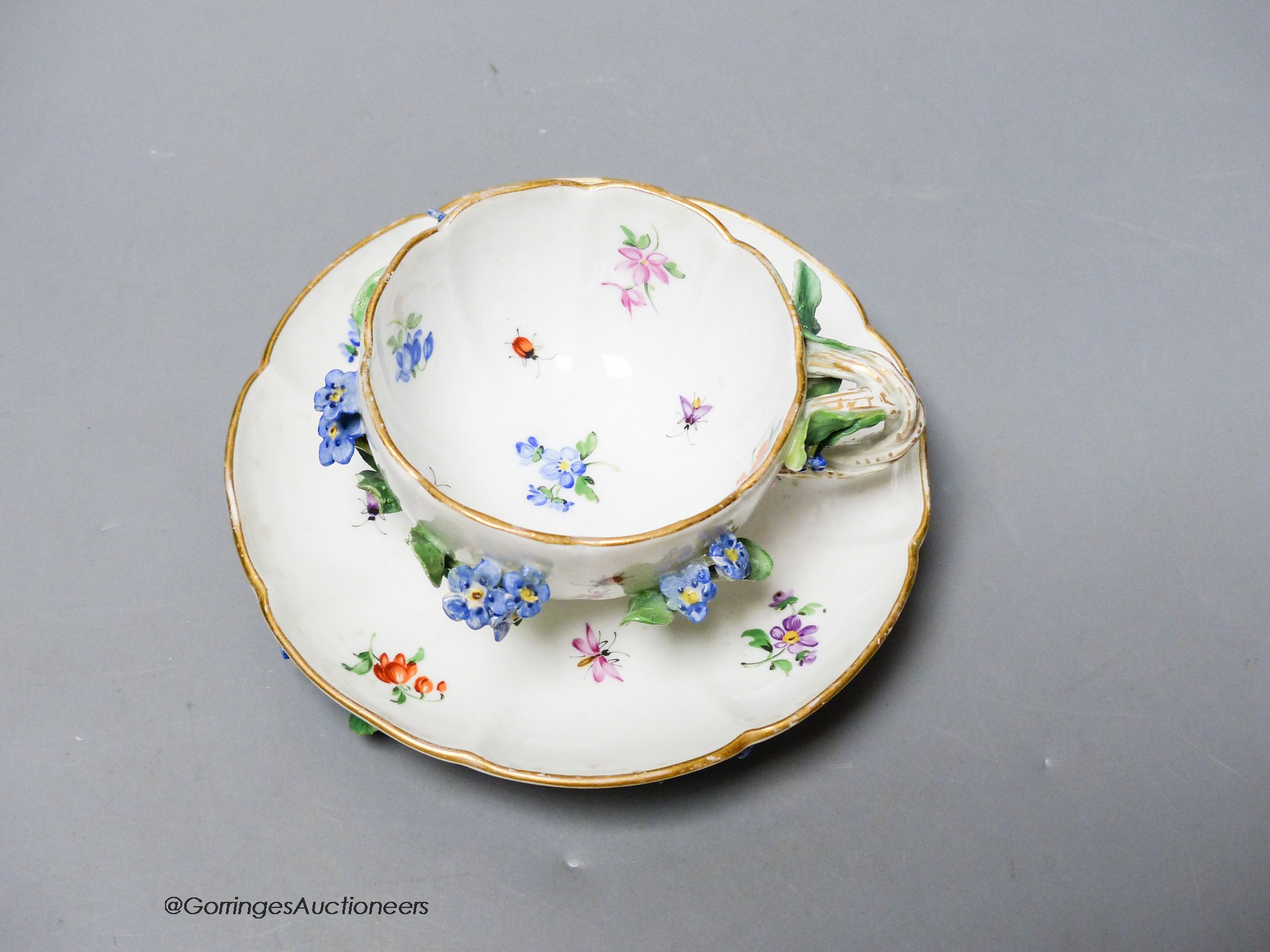 A 19th century Meissen floral encrusted cabinet cup and saucer, decorated with flowers and insects, diameter 12cm